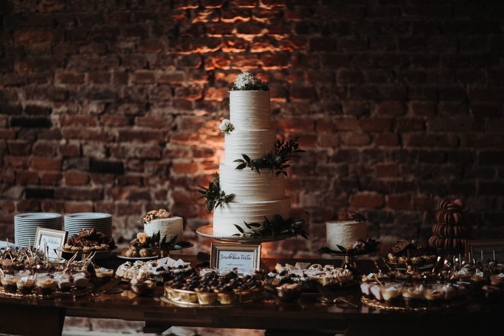 svadobna fotografia torty na pozadi s tehlovou stenou odfotene v boho style v kaviarni slavia v kosiciach spolu so svadobnym candybarom