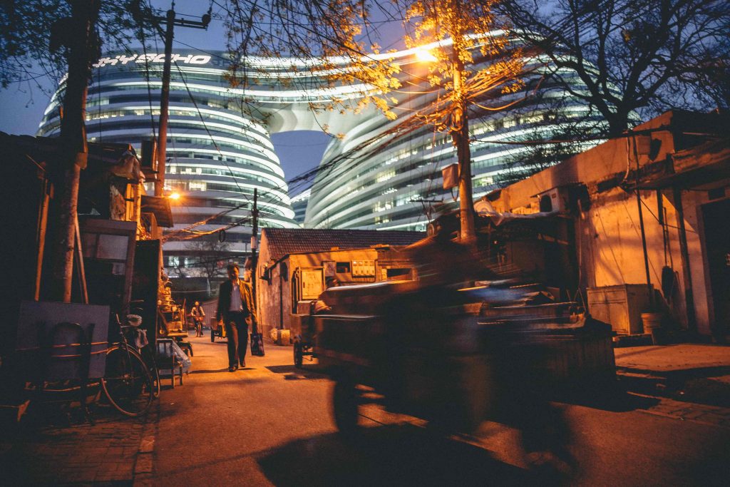 fotka pekingskej chudobnej ulice s modernou architekturou v pozadi