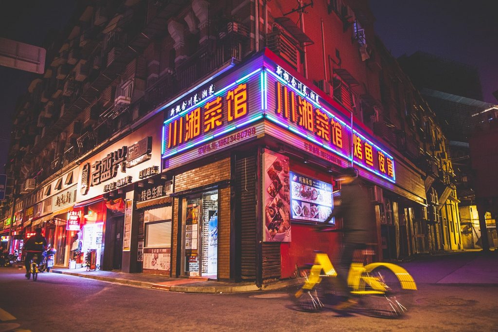 farebna nocna fotka shanghajskej ulice s bicyklistom v pohybe