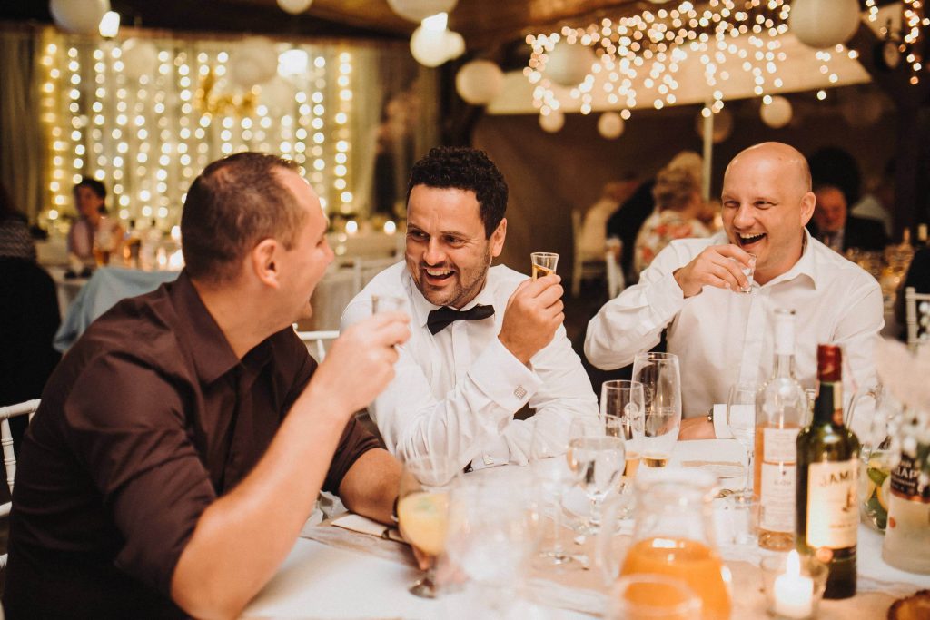 usmievajuci hostia na svadbe si pripijaju s alkoholom