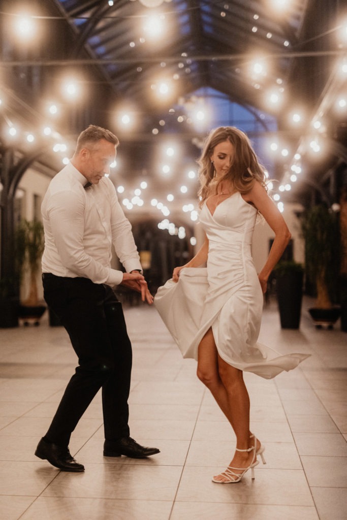 A bride and groom dancing in the hallway of a hotel.