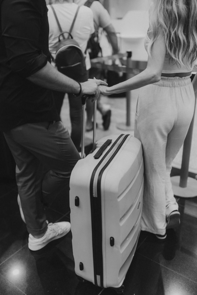 A black and white photo of a couple holding a suitcase.