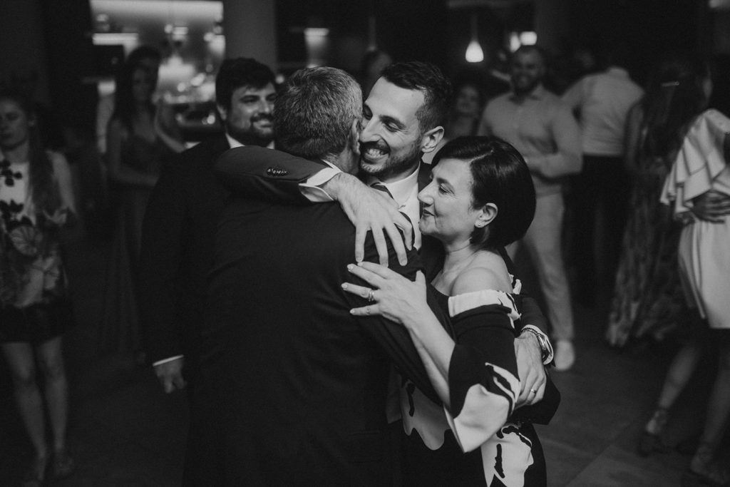 Groom hugging his family in black and white