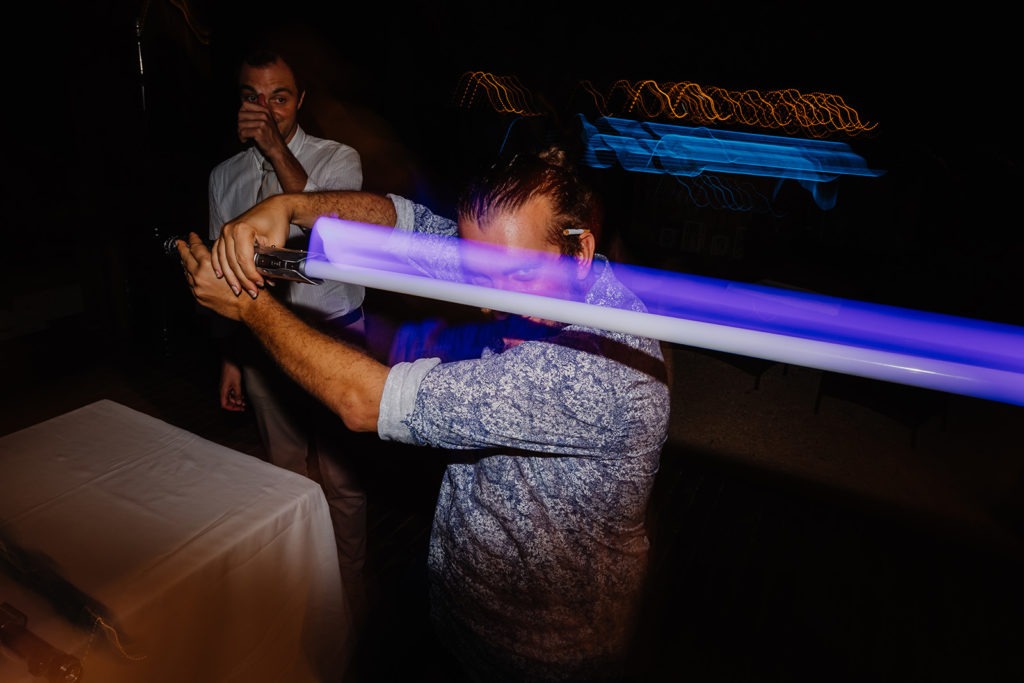 A man holding a blue light saber at a party.