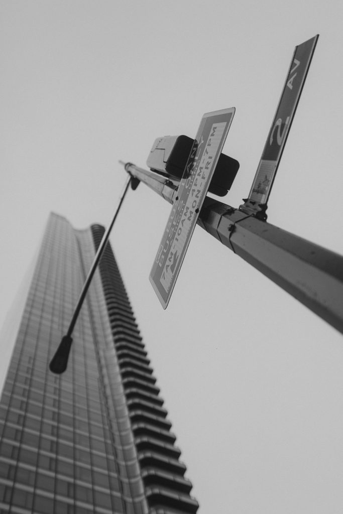 A black and white photo of a street light and a tall building.