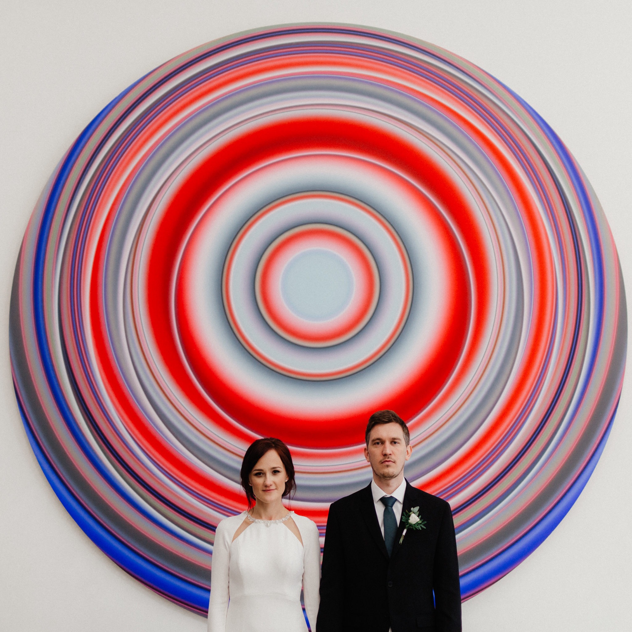 Minimalistic wedding photo of a couple standing in front big art