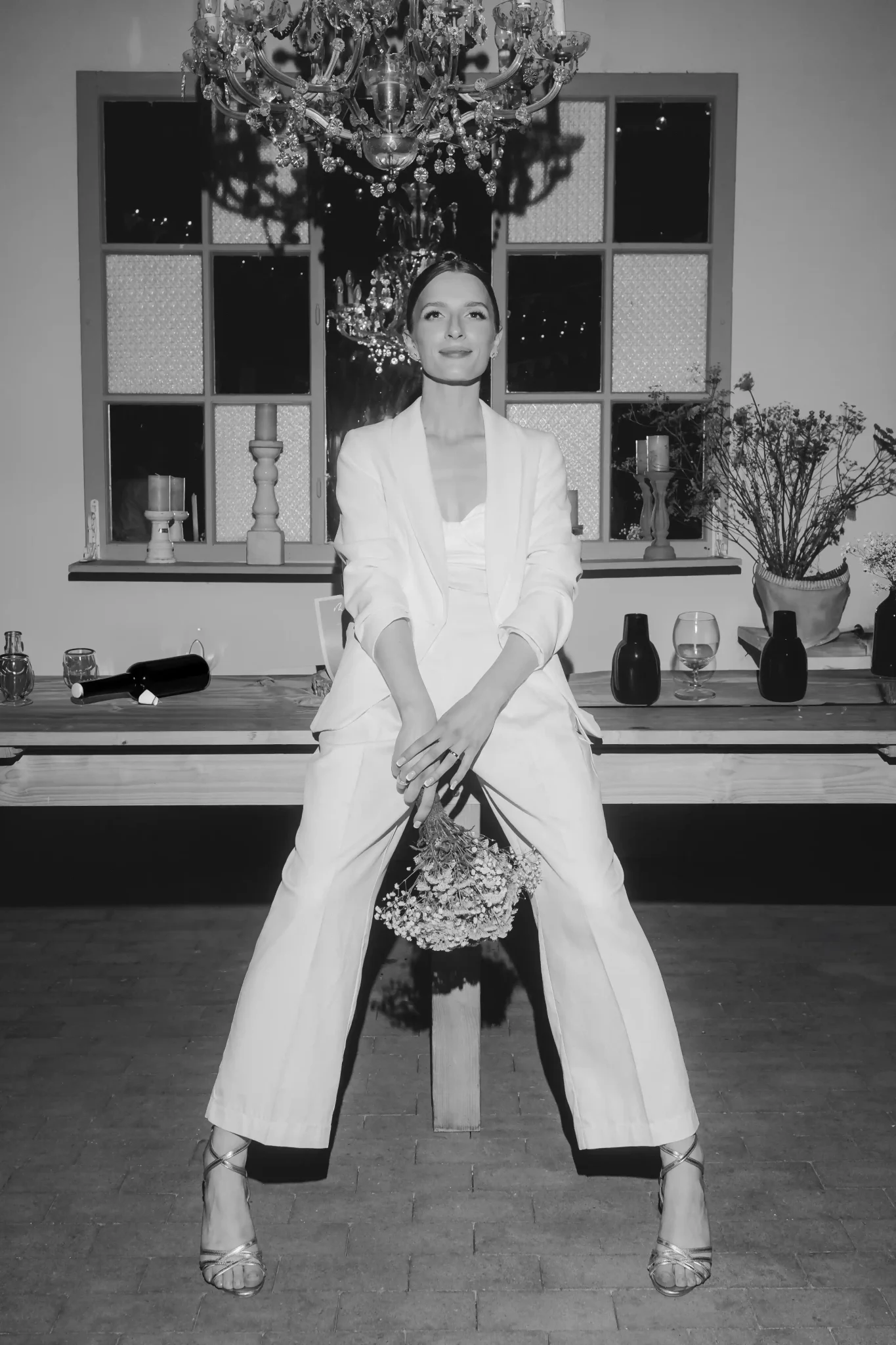 A woman in a white suit sitting on a table.