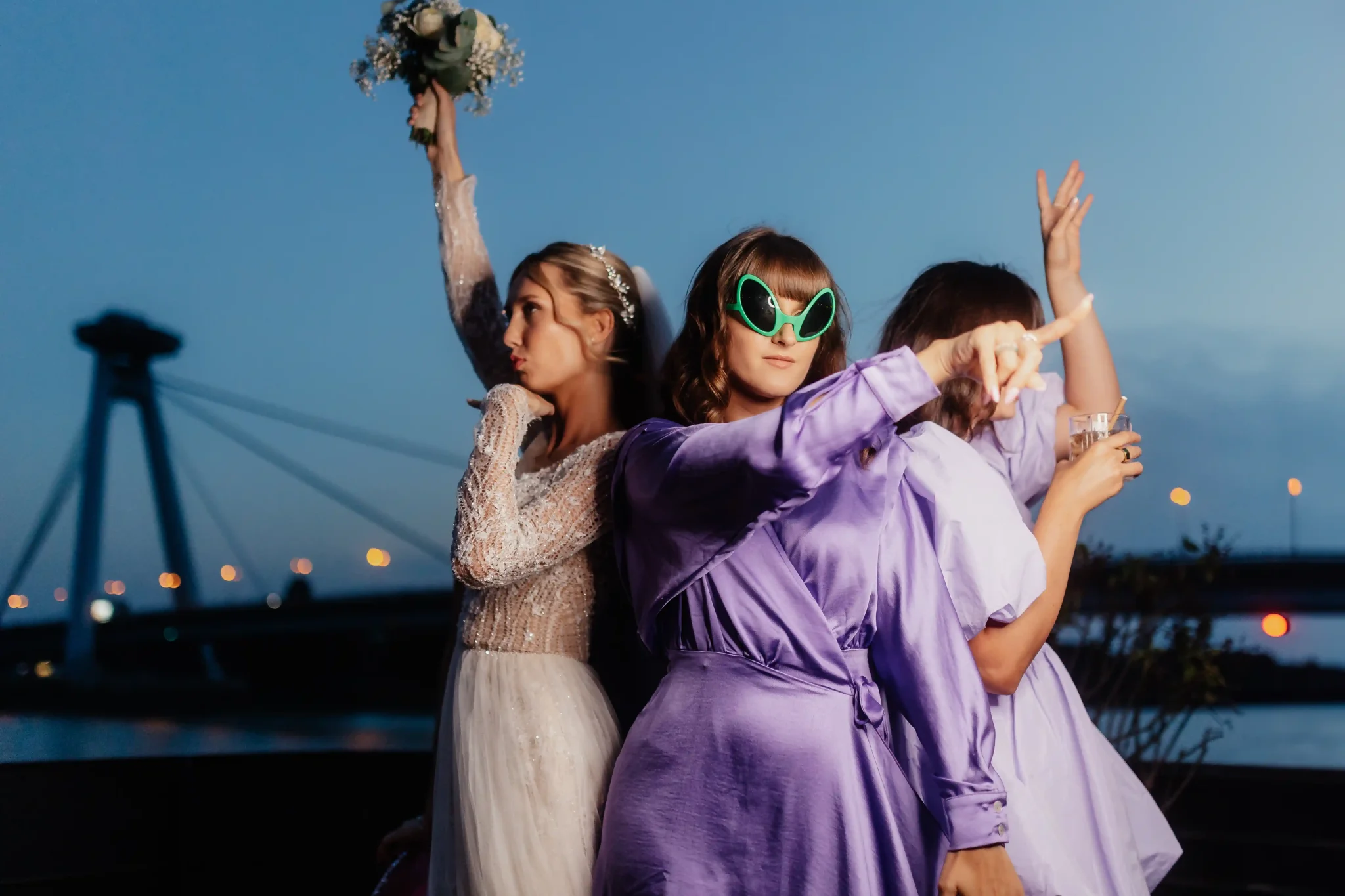 Three bridesmaids posing for a photo on a bridge.