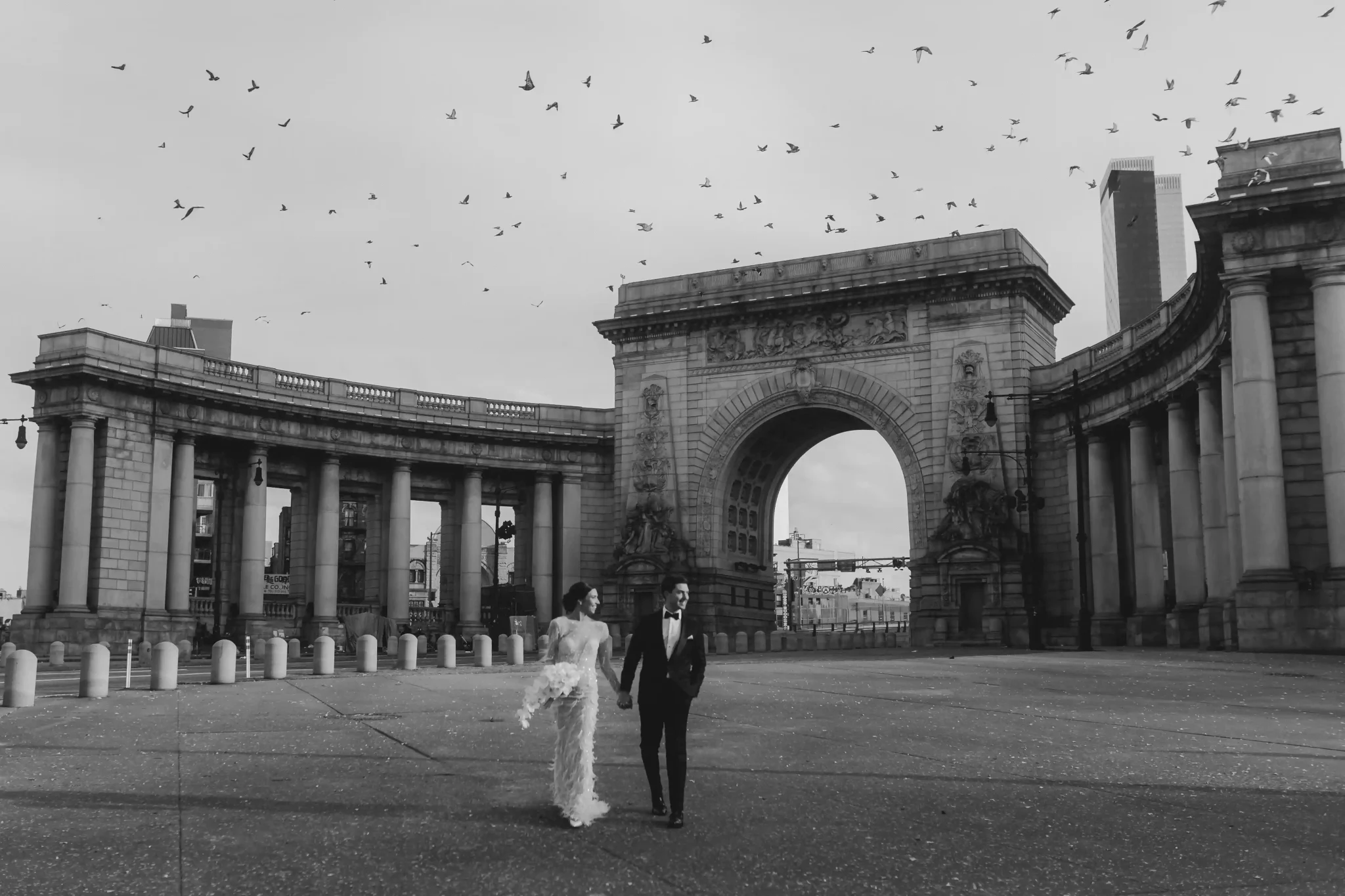 A black and white photo of a bride and groom standing in front of an arch.