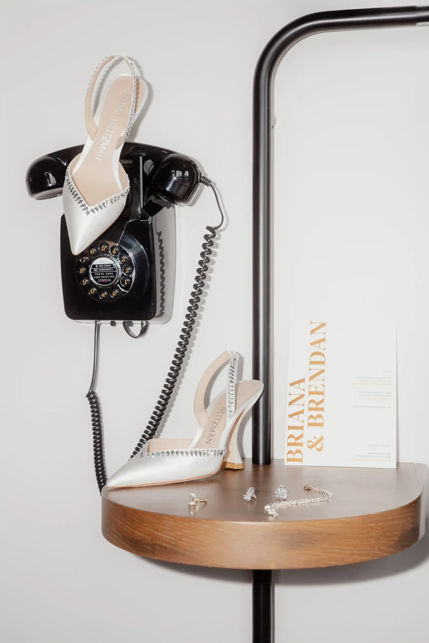 A white telephone with a pair of shoes and a card on it.