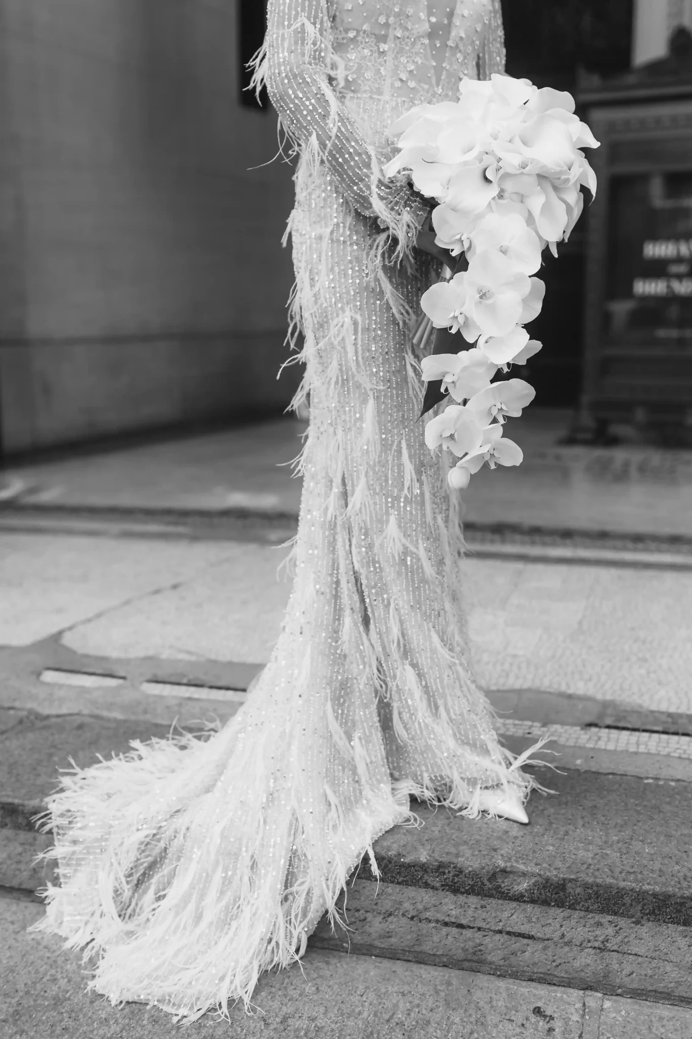 A bride in a feathered wedding dress poses for a photo.