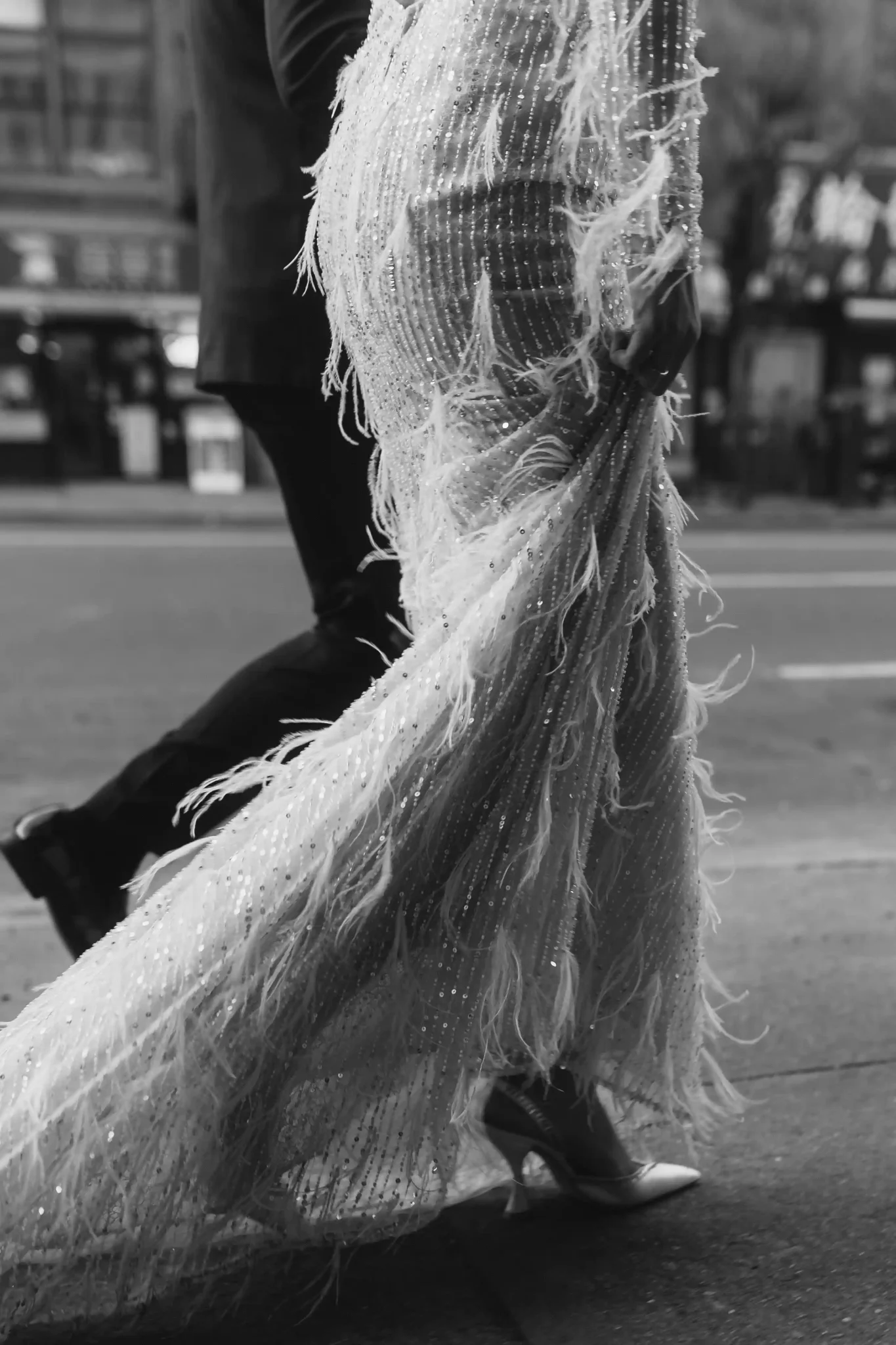 A black and white photo of a bride and groom walking down the street.