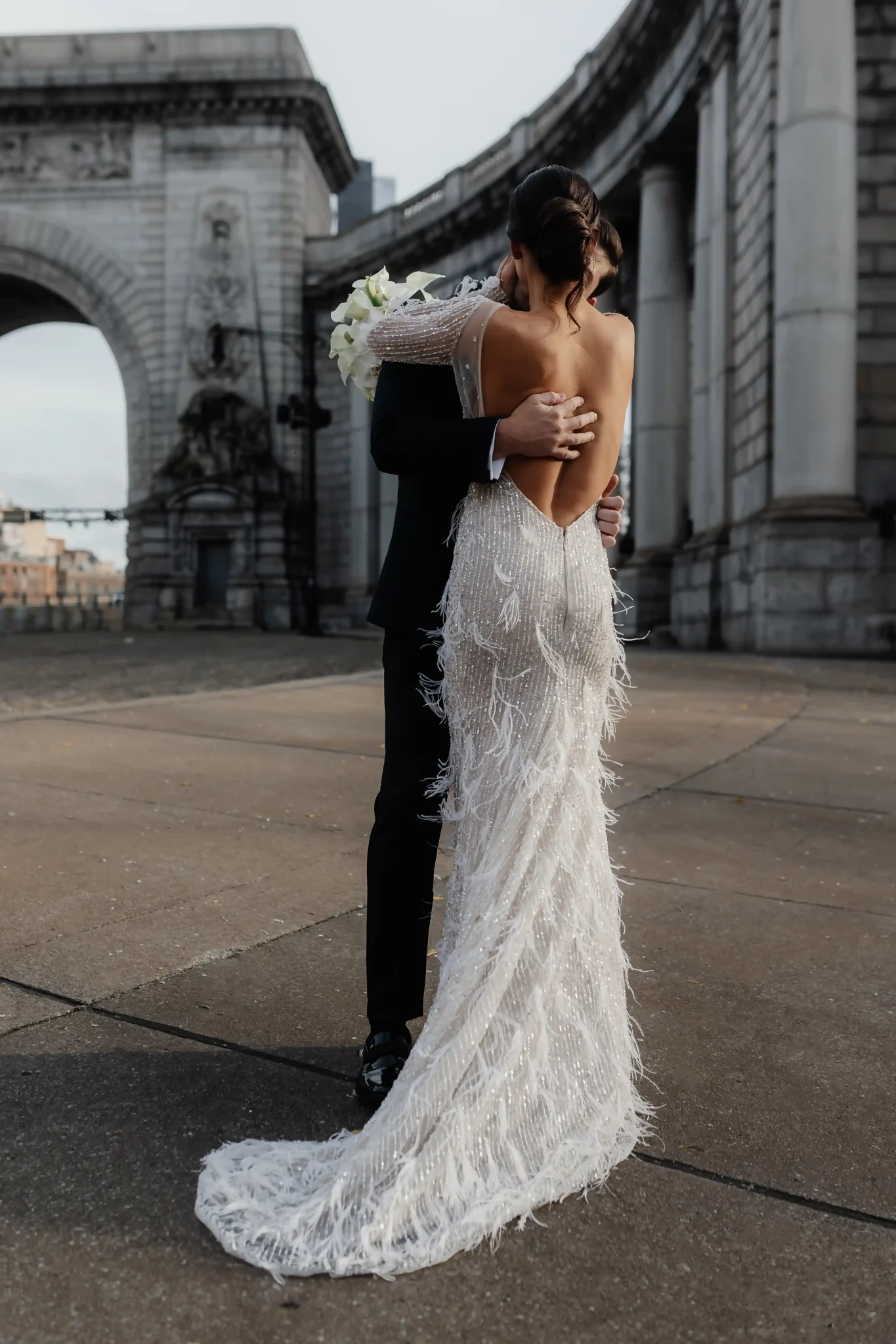 A bride and groom hugging in front of an arch.