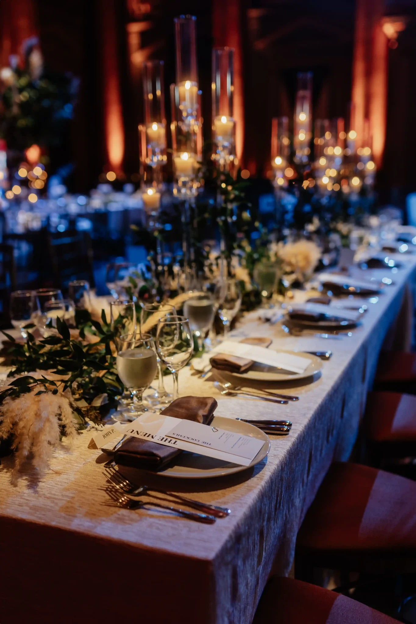 A table set with candles and greenery.