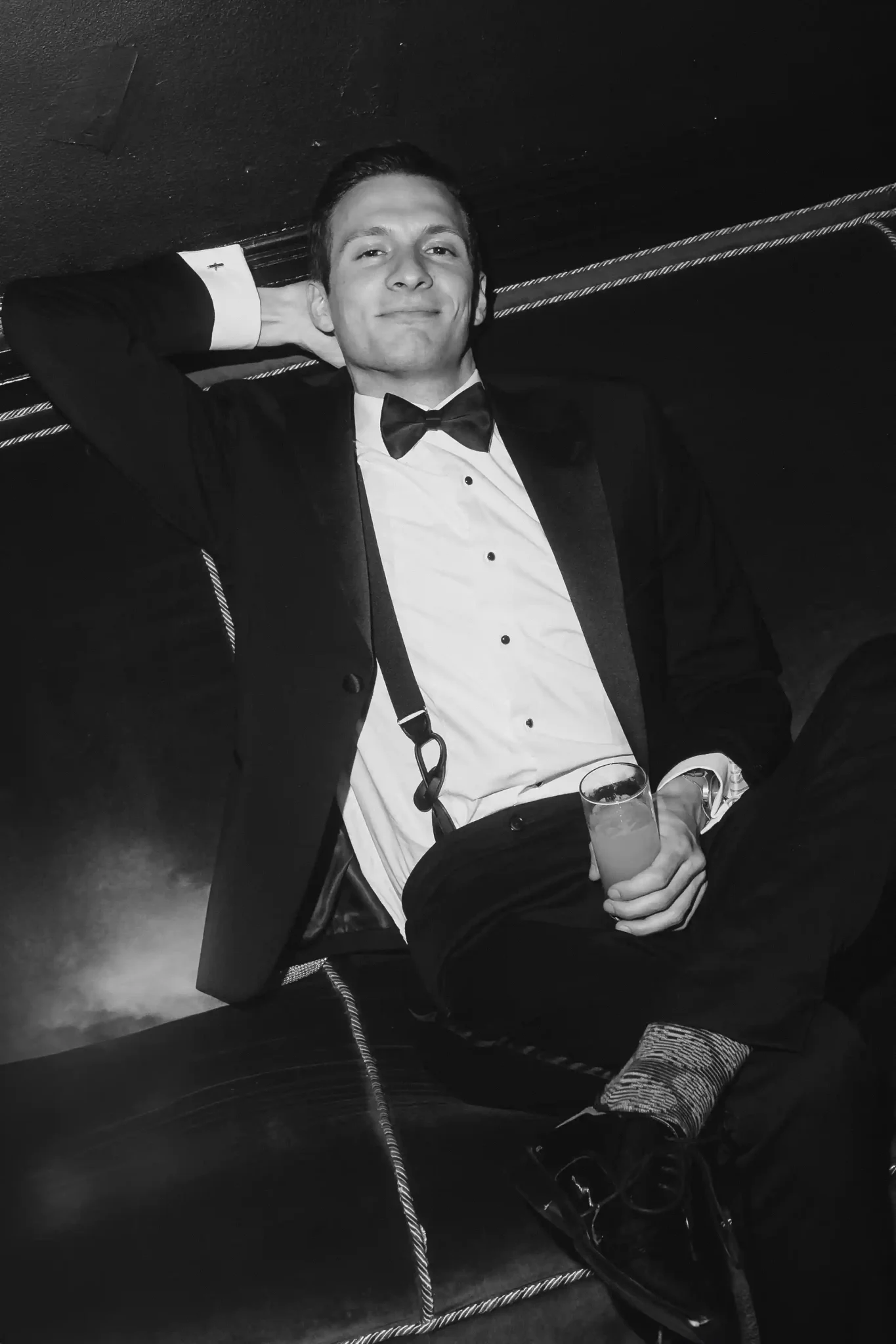 A man in a tuxedo sitting on a couch.