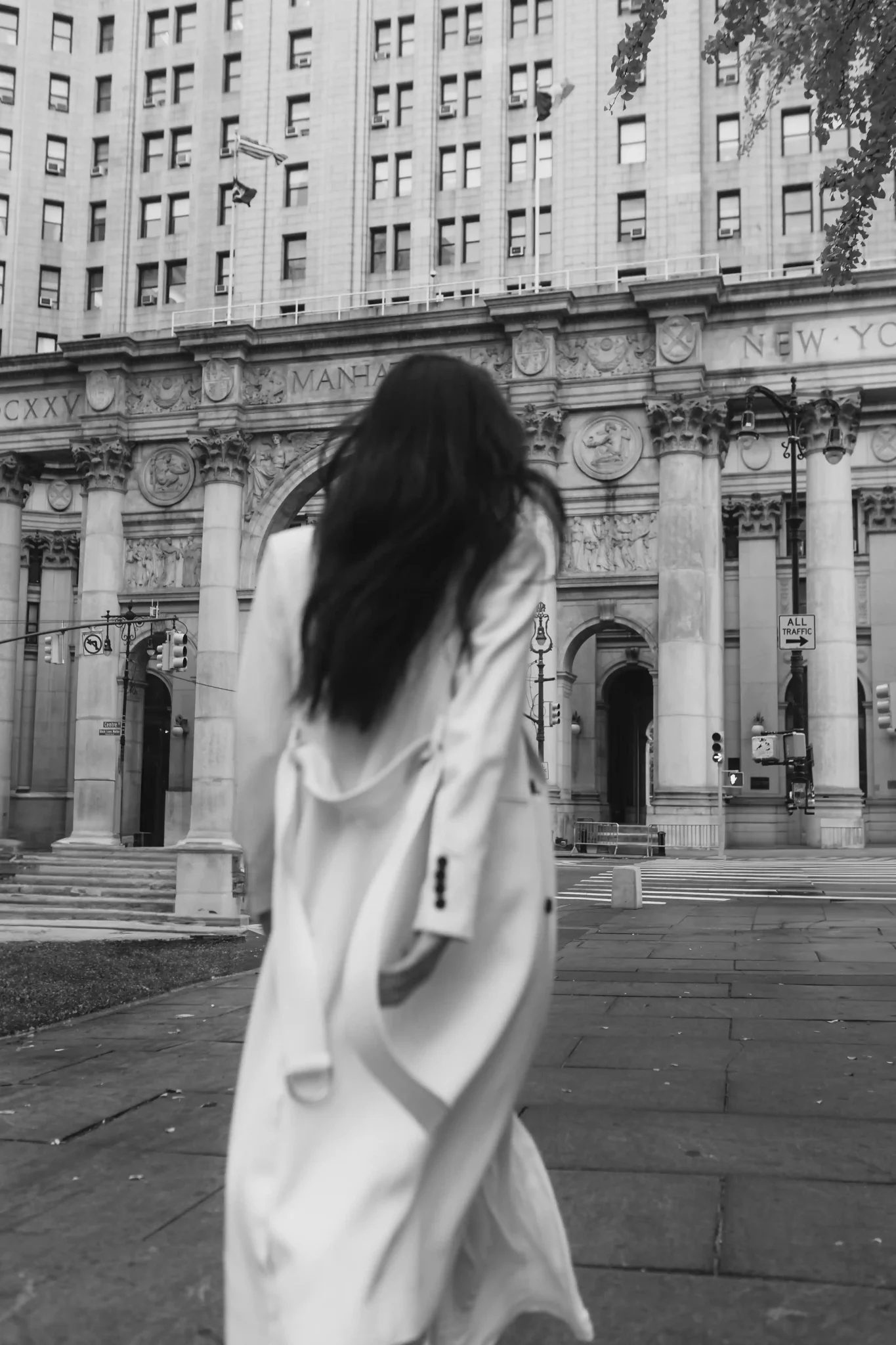A woman in a white coat walking in front of a building.