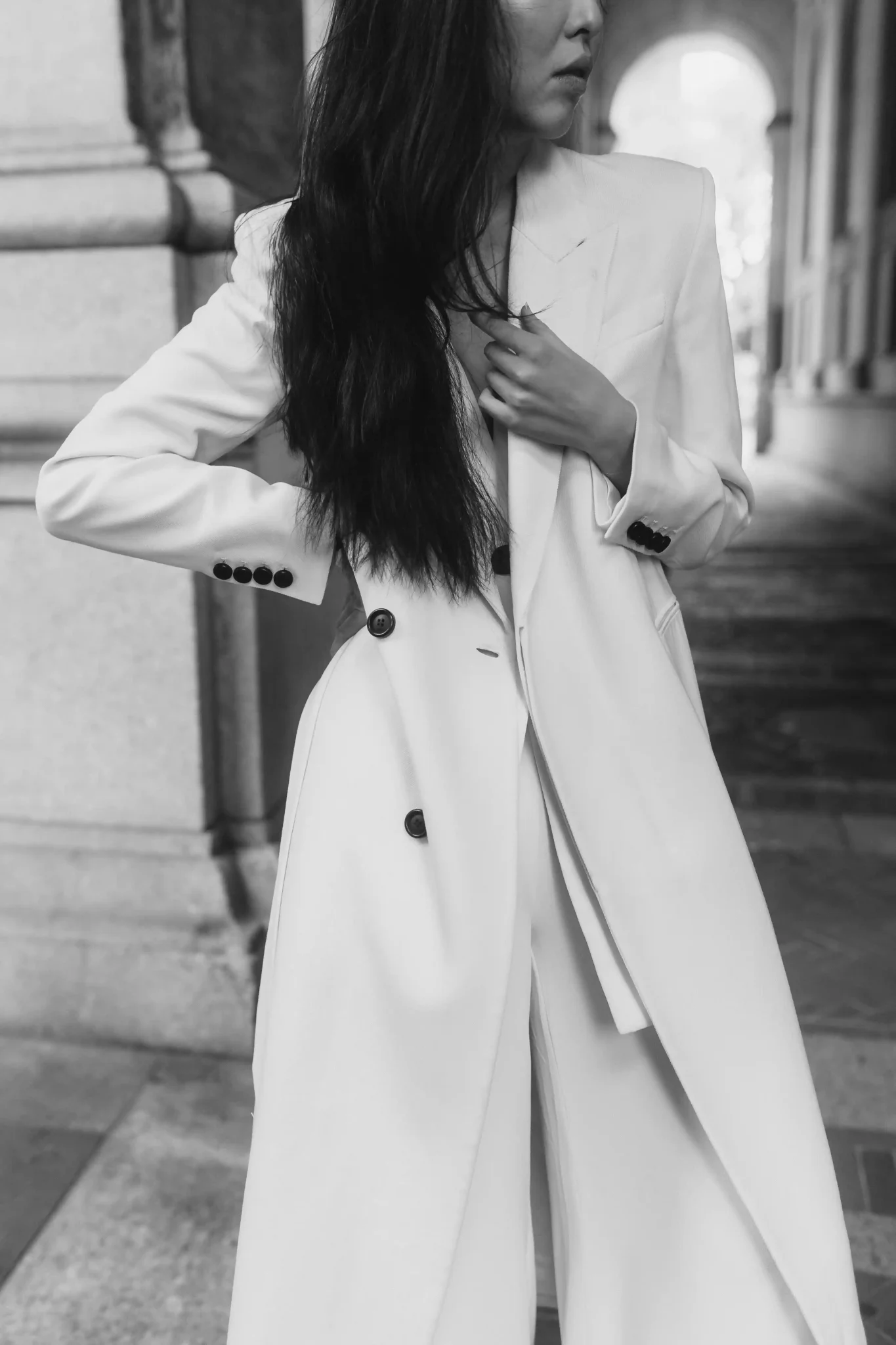 A woman in a white suit posing on a street.
